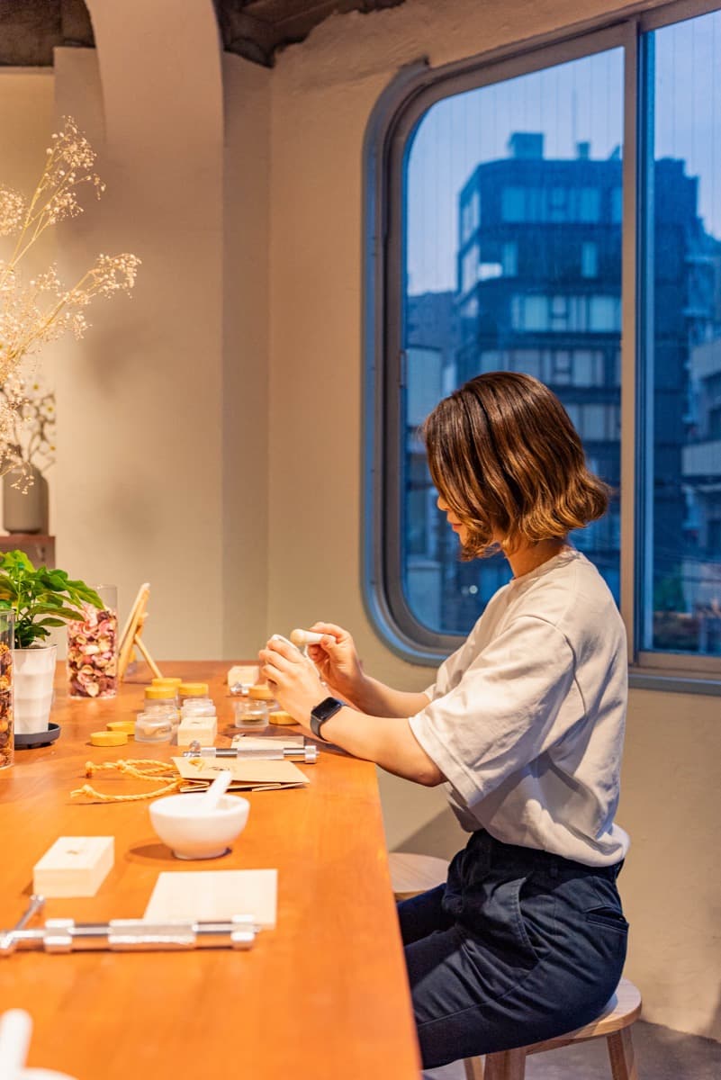 A guest holding finished incense at a seat by the window